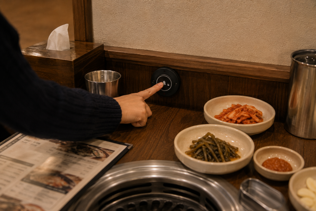 Why Do Koreans Press a Bell Instead of Calling a Waiter? A customer pressing a call button to request service at a Korean restaurant table.