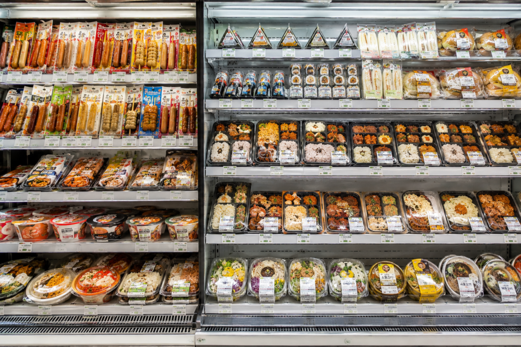 Why Do Koreans Visit Convenience Stores So Often? Korean convenience store refrigerated section featuring lunch boxes, kimbap, sandwiches, and ready-to-eat meals.