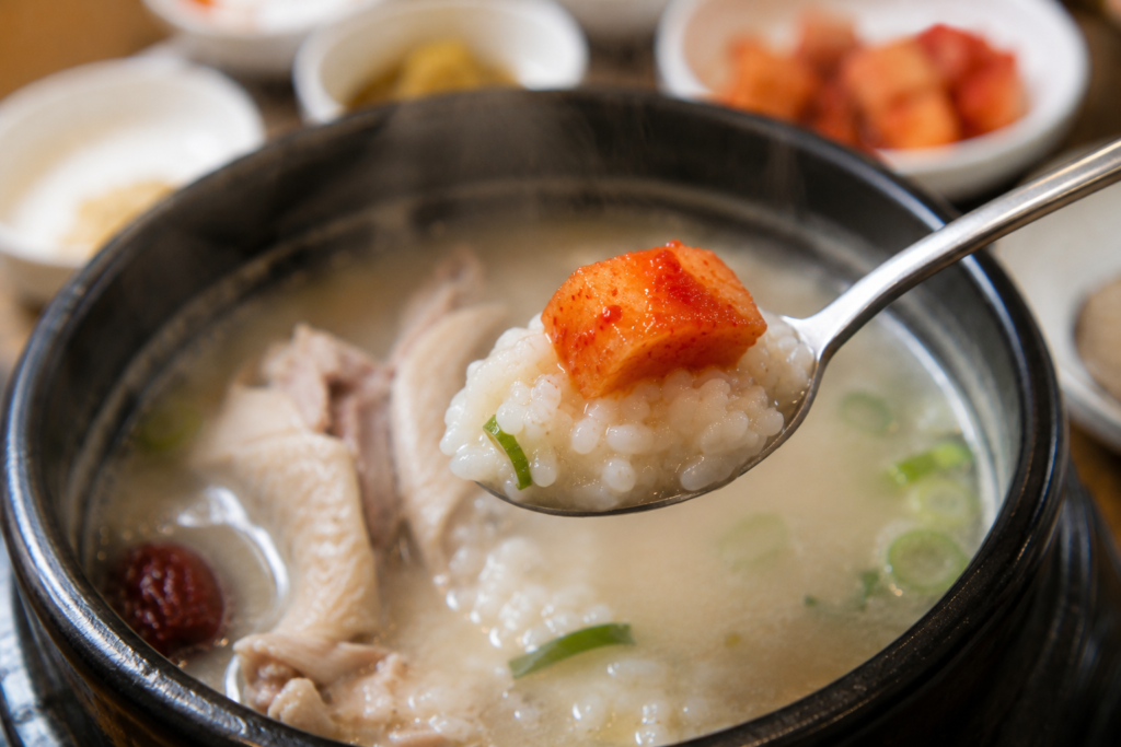 Why Do Koreans Eat Hot Chicken Soup in Summer? Spoonful of rice porridge from Korean samgyetang topped with a piece of kkakdugi radish kimchi.